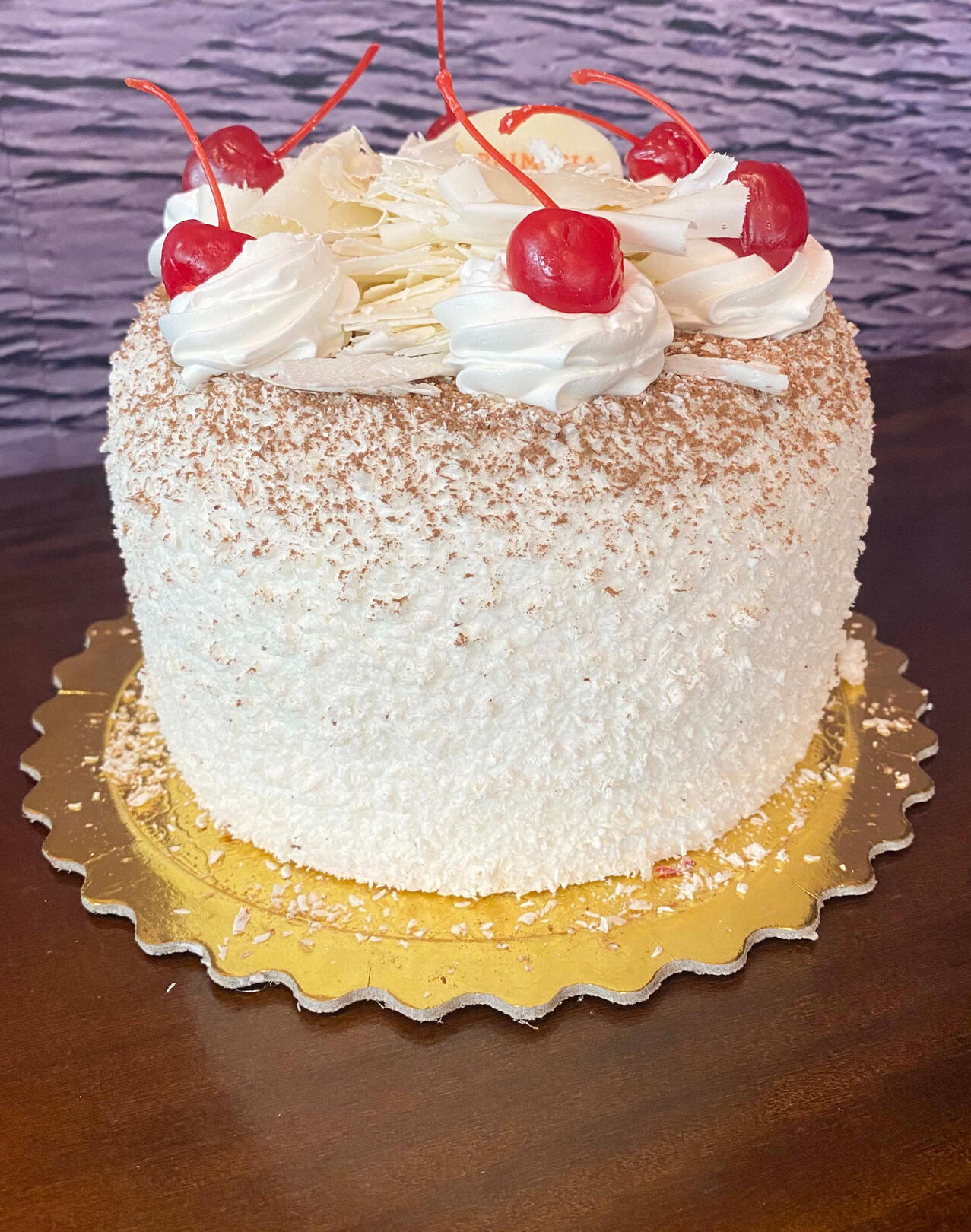 413-FLORESTA BRANCA Massa de pão de ló branco. Recheado com chantilly e cerejas picadas. Coberto com chantilly. Decorado com raspas de chocolate branco e cerejas.